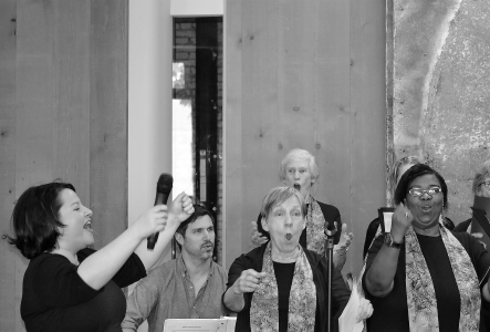 Singing female with arms raised in front of a choir