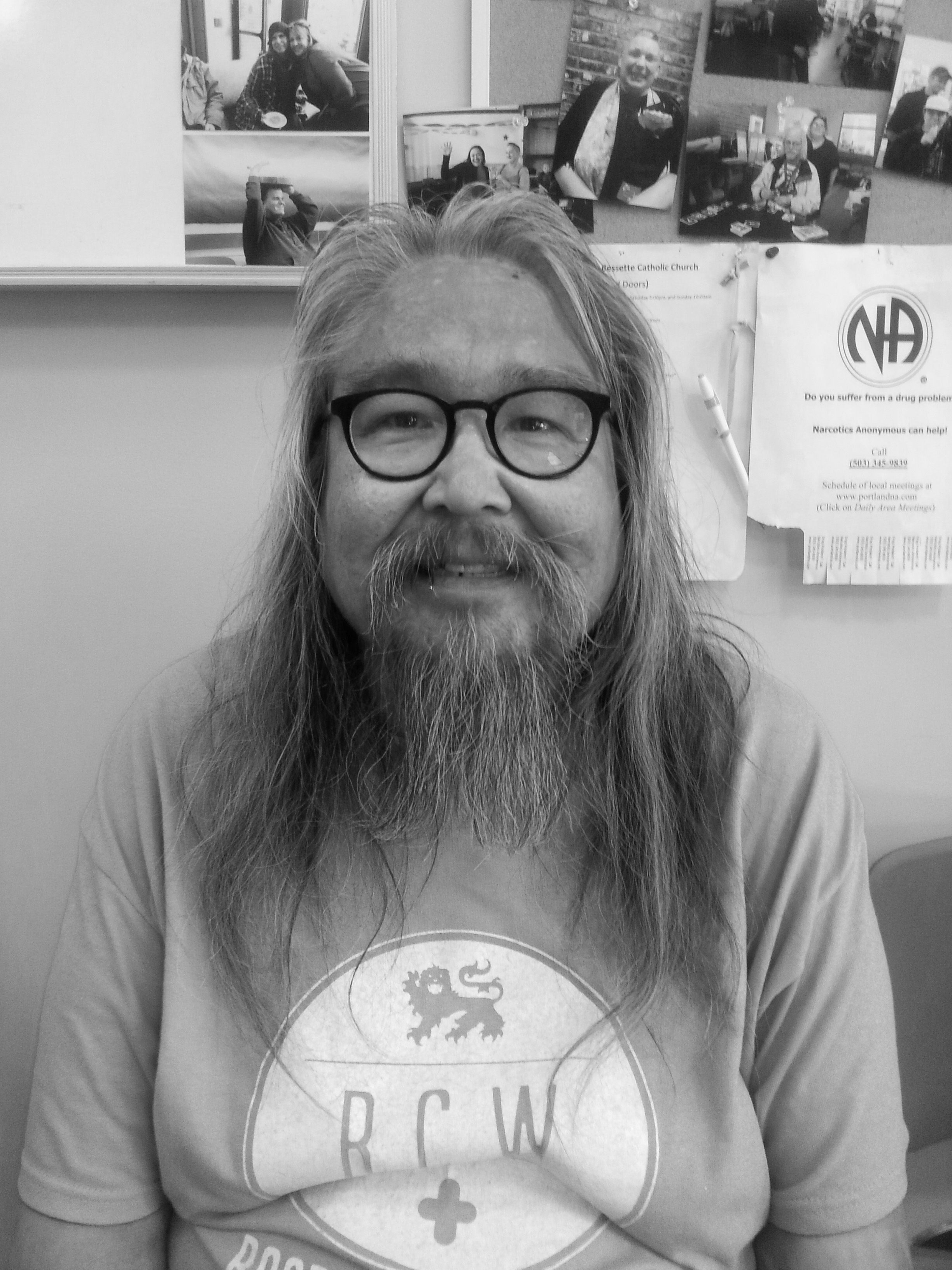 A person with long hair, a beard, and glasses starring forwards