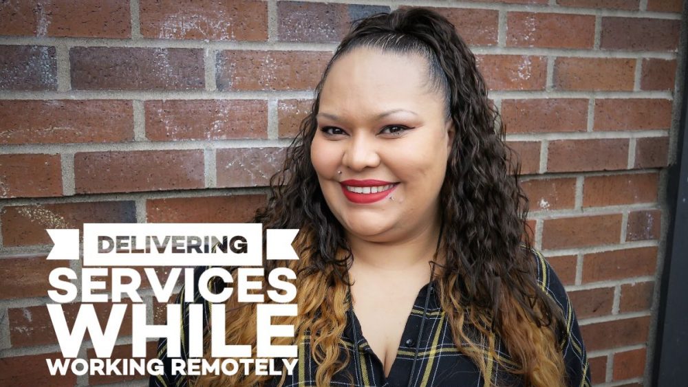 Smiling female with long black hair standing in front of a brick wall with the text "Delivering services while working remotely"