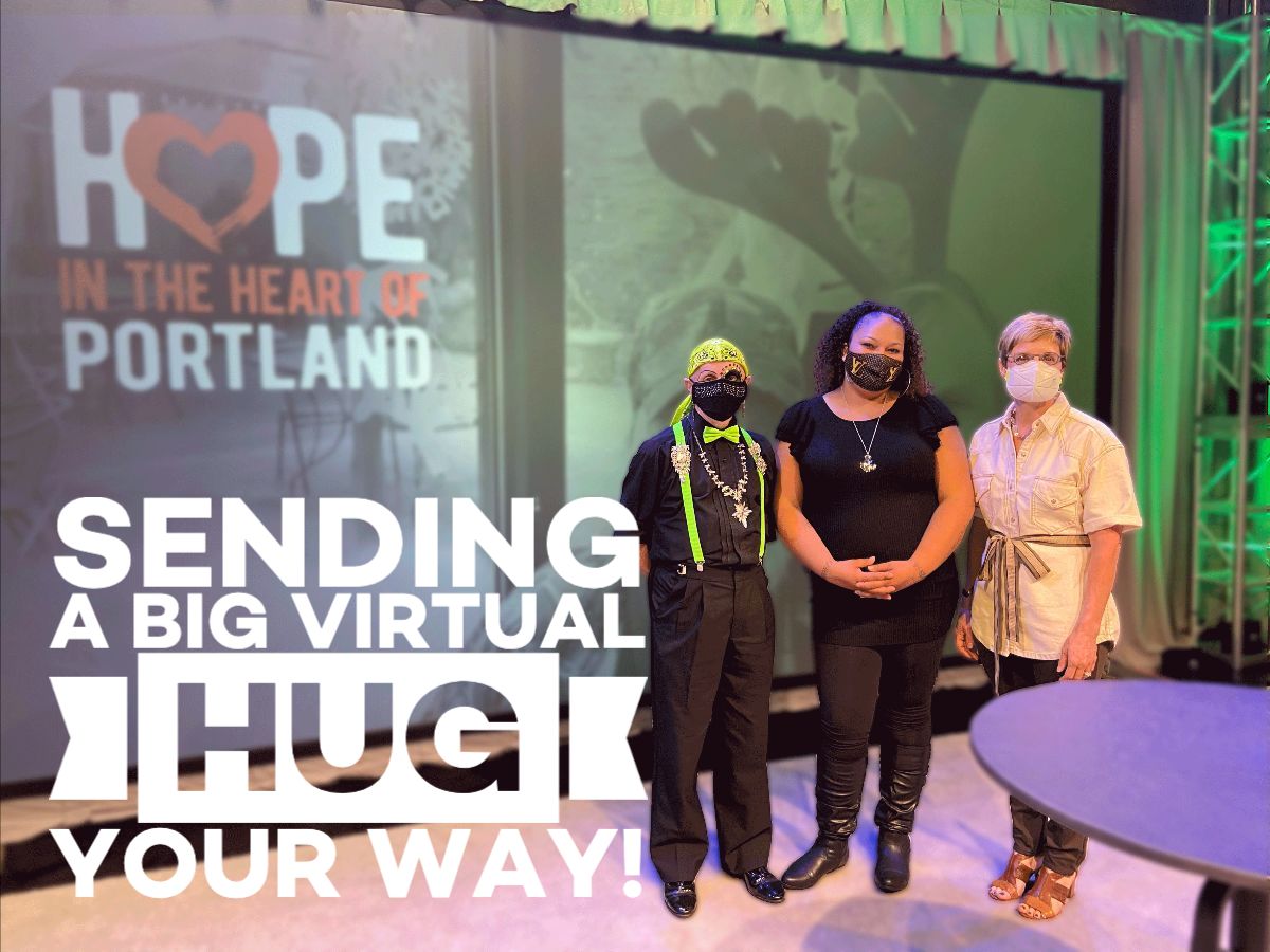 Picture of three people in masks in front of an electronic screen with the words "Sending a big virtual hug your way"