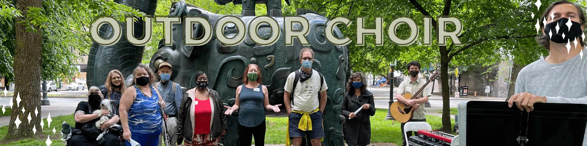 A group of people outdoors in front of a statue with the words 'outdoor choir'