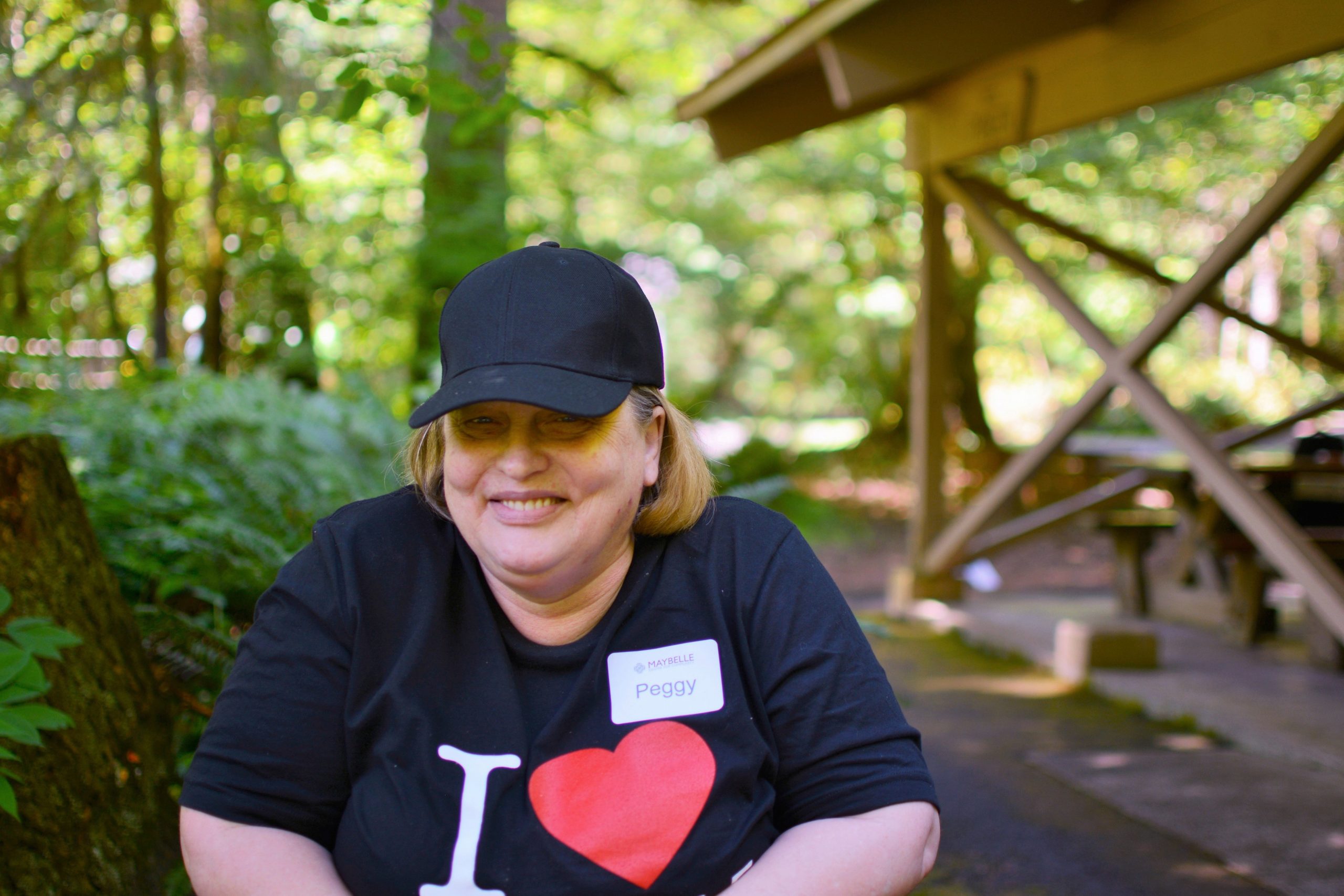 Smiling female outside, with a hat on, sitting on her walker