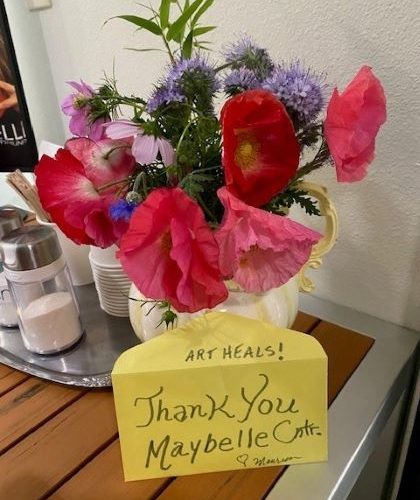 Small bouquet of red, pink, and purple flowers with a yellow note reading 'Art Heals! Thank You Maybelle Center'