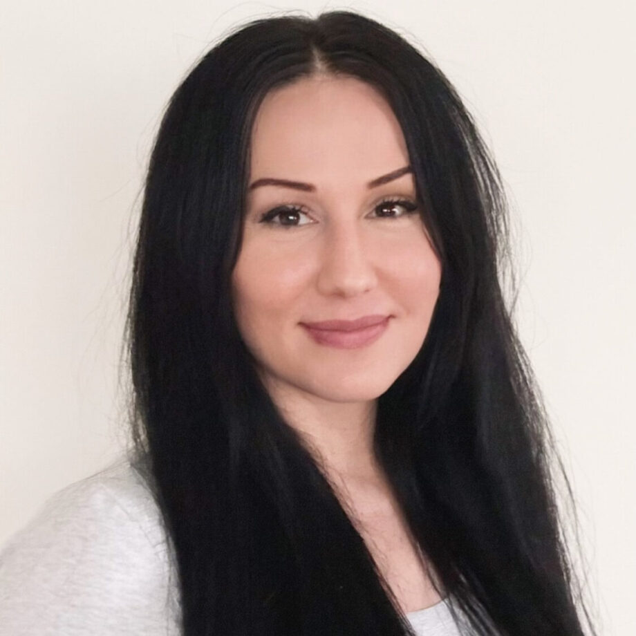 White woman with long dark hair smiles directly at the camera